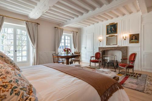 a bedroom with a bed and a table and a fireplace at Le Presbytère - demeure d'exception historique in Biéville-en-Auge