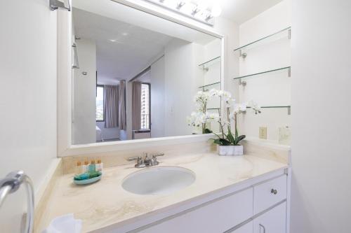 a bathroom with a sink and a large mirror at Mountain View Oasis, Steps from Beach with Parking! in Honolulu