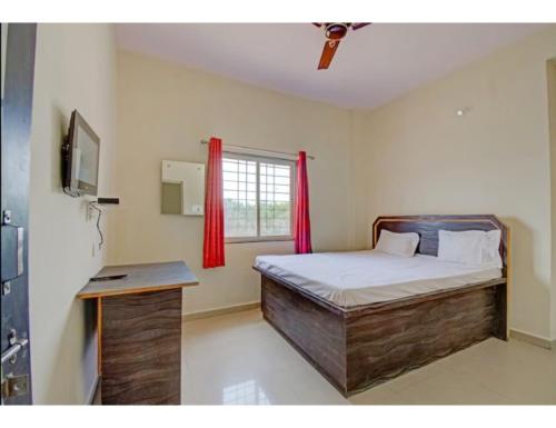 1 dormitorio con 1 cama y una ventana con cortinas rojas en Hotel Chandrajyoti, Deoghar, en Deoghar