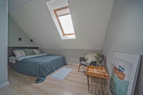 a bedroom with a bed and a chair and a window at Apartamenty Nadmorska Osada in Łeba