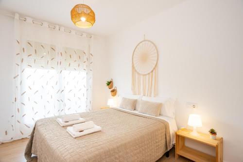 a white bedroom with a bed with two towels on it at Empuriabrava Apartaments No 5 in Empuriabrava