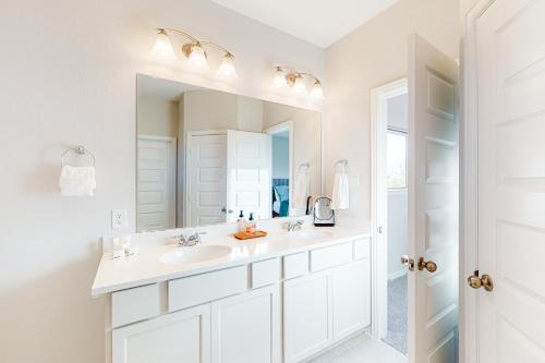 Baño blanco con lavabo y espejo en Clear Lake Shores en Seabrook