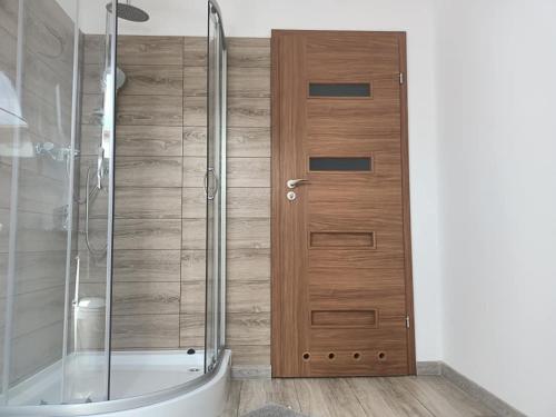 a bathroom with a shower and a wooden door at Pokoje u Izy Stare Kiejkuty in Szczytno