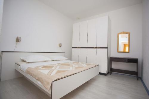 1 dormitorio blanco con 1 cama grande y espejo en Apartments Dino, en Makarska