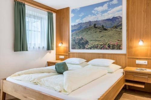 a bed in a bedroom with a painting on the wall at Feldererhof Apt Hochstein in Santa Maddalena