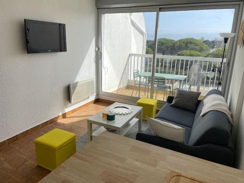 d'un salon avec un canapé et une table ainsi que d'un balcon. dans l'établissement Joli Studio Cabine - Port Camargue - Plage Sud, au Grau-du-Roi
