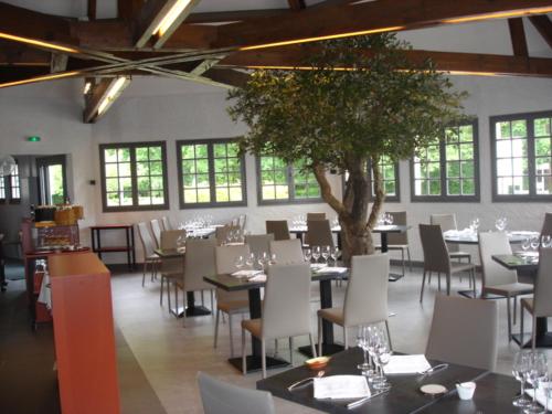 a dining room with tables and chairs and a tree at Hotel-Restaurant Du Lac in Joue-les-Tours
