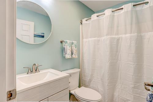 uma casa de banho com um lavatório, um WC e um espelho. em Bert's Bungalow em Carolina Beach