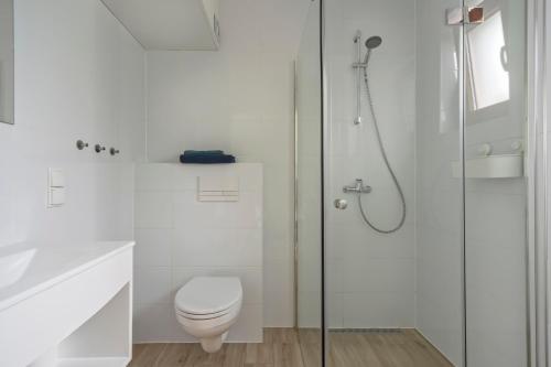 a white bathroom with a toilet and a shower at Apartamenty Nadmorska Osada in Łeba