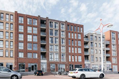 een groot bakstenen gebouw met auto's geparkeerd voor het bij BizStay Harbour III Scheveningen Apartments in Scheveningen