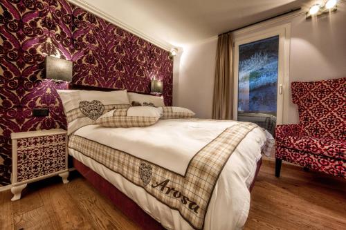 a bedroom with a bed and a red wall at Home Hotel Arosa in Arosa