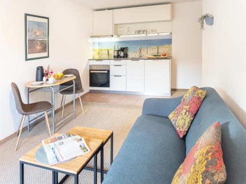 a living room with a blue couch and a kitchen at Gut Vorwerk in Sagard