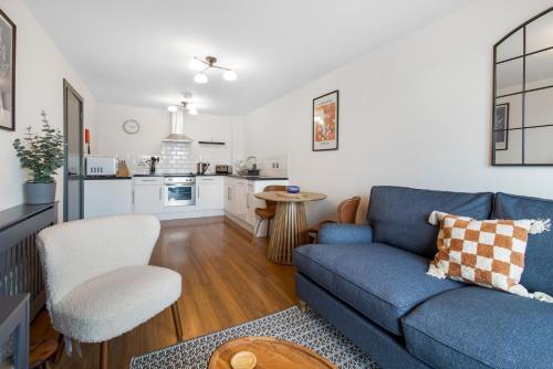 ein Wohnzimmer mit einem blauen Sofa und einer Küche in der Unterkunft Central 1 BD + Sofa Bed in the Heart of Cheltenham! in Cheltenham
