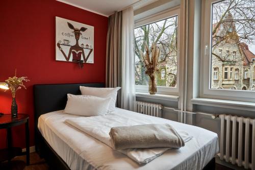 Schlafzimmer mit einem Bett mit roten Wänden und einem Fenster in der Unterkunft Boutique Hotel am Markt in Melle