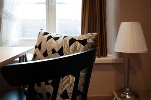 einem schwarzen Stuhl mit einem Kissen vor dem Fenster in der Unterkunft Hotel Restaurant Post in Bözen