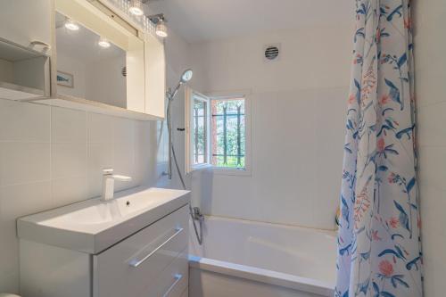 uma casa de banho com um lavatório e uma cortina de chuveiro em La Pélagie - Maison climatisée vue mer em Sainte-Maxime