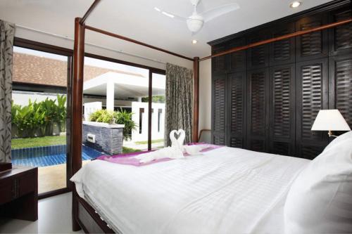 a bedroom with a large white bed with a window at Exotic Boutique 4BR Pool Villa Toya, Gated Residence, Rawai in Ban Saiyuan (1)