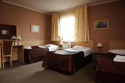 a hotel room with two beds and a window at Hotel Carskie Koszary in Zamość