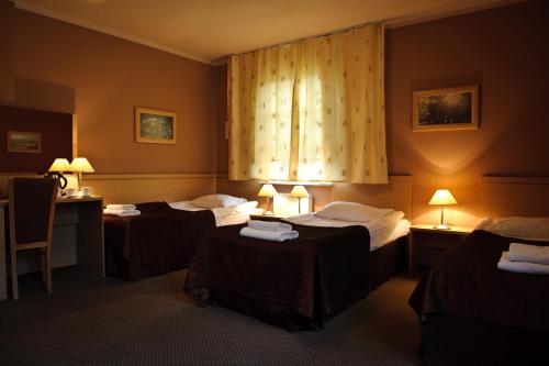 a hotel room with three beds and a window at Hotel Carskie Koszary in Zamość