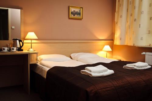 a hotel room with a bed with towels on it at Hotel Carskie Koszary in Zamość