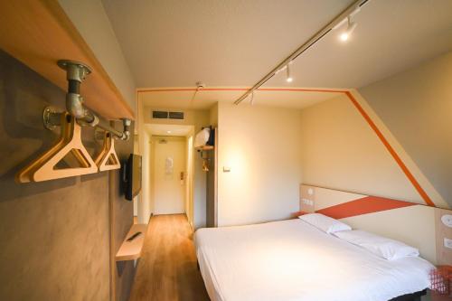 een slaapkamer met een wit bed in een kamer bij ibis budget Site du Futuroscope in Chasseneuil-du-Poitou