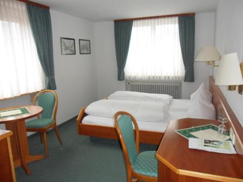 um quarto de hotel com uma cama, uma mesa e cadeiras em Landgasthof mit Gästezimmer Frohe Einkehr em Friburgo em Brisgóvia