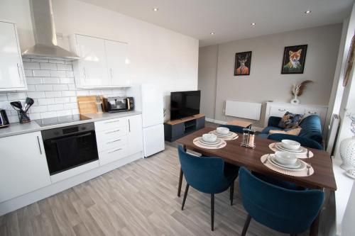 uma cozinha e sala de estar com uma mesa e cadeiras azuis em Ideal Lodgings in Walkden 