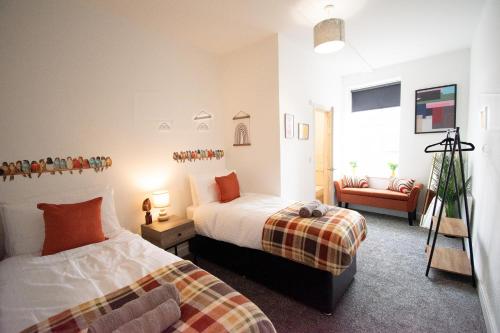 a bedroom with two beds and a chair and a window at Ideal Lodgings in Walkden 