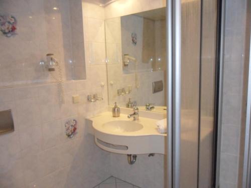 een witte badkamer met een wastafel en een douche bij Landgasthof mit Gästezimmer Frohe Einkehr in Freiburg im Breisgau