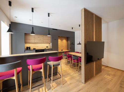 una cucina e una sala da pranzo con un bar con sgabelli rosa di Salzkammergut Lodge a Ebensee
