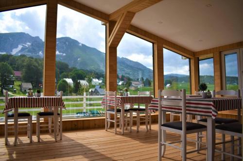 une terrasse couverte avec tables et chaises et vue sur les montagnes dans l'établissement Vilino Kolo - Virak, à Žabljak