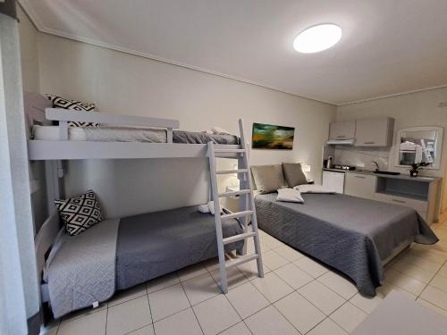 sypialnia z 2 łóżkami piętrowymi i kuchnią w obiekcie Aretousa w mieście Tolo