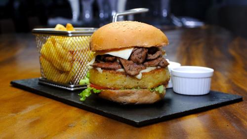 a sandwich on a black plate with a basket of fries at CITY HOTEL in Antananarivo