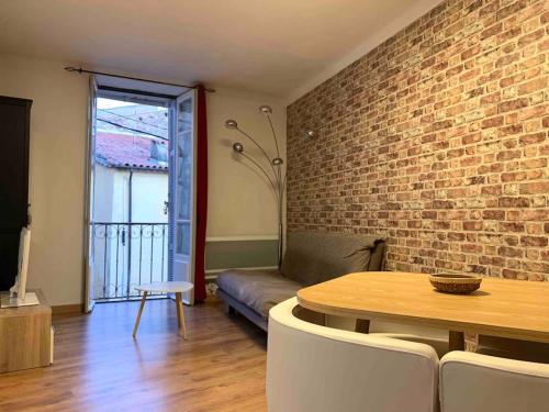 a living room with a table and a brick wall at Fréjus • Village Historique • Superbe T3 • 50m2 • in Fréjus