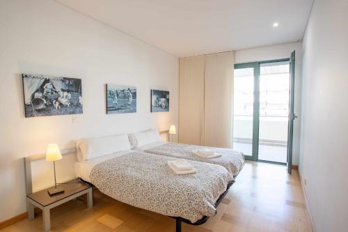 Dormitorio blanco con cama y puerta de cristal en Marina Vilamoura Aquamar 215 VilamouraSun, en Vilamoura