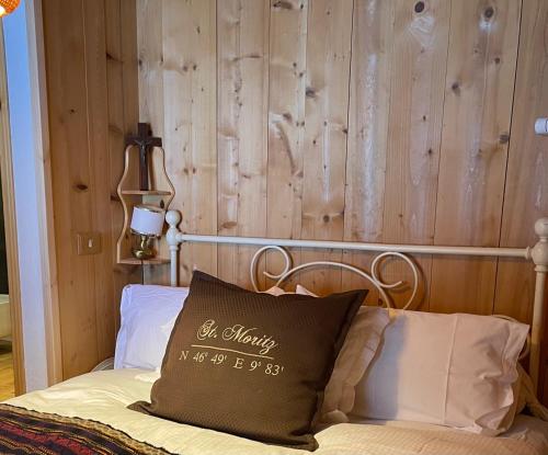 a bed with a wooden wall with a pillow on it at Chalet Leonard House in the wood in Pennabilli