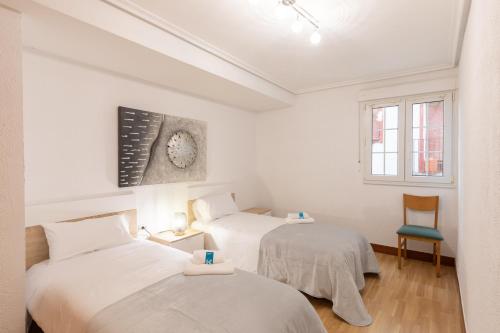 2 camas en una habitación con paredes blancas en Ibirriaga - baskeyrentals en Mutriku