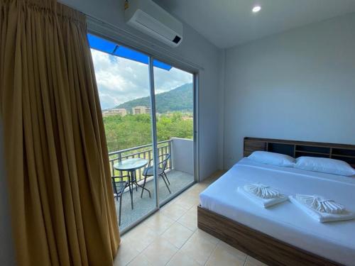 a bedroom with a bed and a large window at L&P Guesthouse in Kata Beach