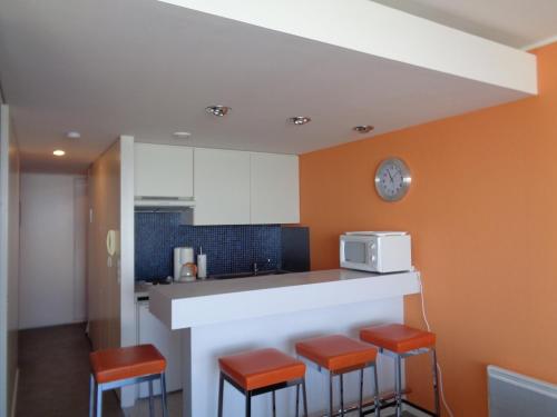 une cuisine avec des murs orange et un comptoir avec des tabourets dans l'établissement Appartement T2 au centre d'Arcachon avec balcon vue bassin et parking - FR-1-374-51, à Arcachon