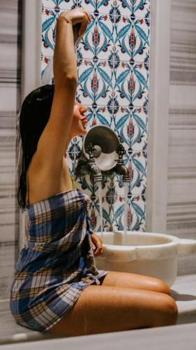 a woman sitting on the floor in front of a sink at Faustina Hotel & Spa in Güzelçamlı