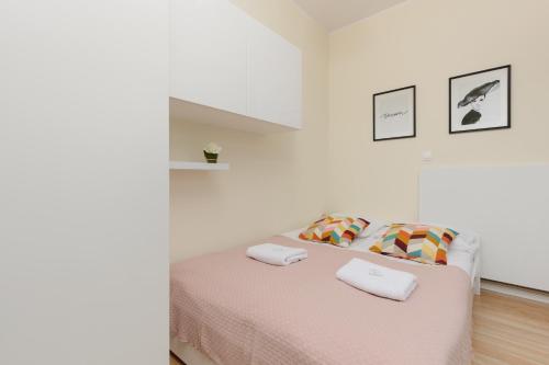 a white bedroom with a bed with two towels on it at Niemcewicza Pet-Friendly Apartment by Renters in Warsaw