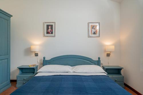 1 dormitorio con 1 cama azul y 2 mesas azules en Su Cannonariu, en Orosei