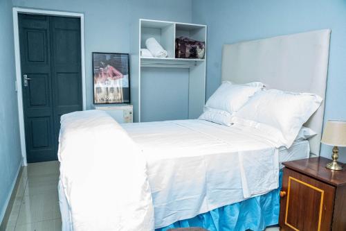 a bedroom with a white bed and a blue wall at Lancaster Guest House in Boksburg