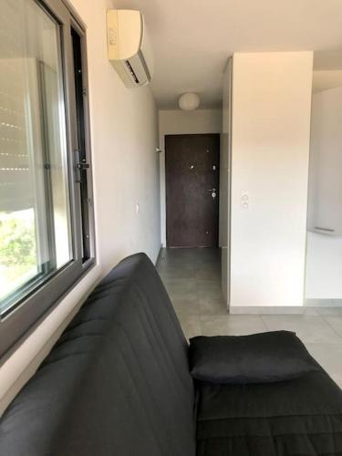 un salon avec un canapé et une fenêtre dans l'établissement Studio Piscine, 200m port de Porto Vecchio pour 2 personnes, à Porto-Vecchio