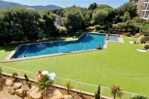 une grande piscine avec une pelouse verdoyante dans l'établissement Studio Piscine, 200m port de Porto Vecchio pour 2 personnes, à Porto-Vecchio