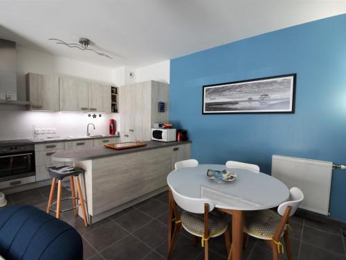 une cuisine avec une table blanche et un mur bleu dans l'établissement Arcachon - T3 calme et spacieux avec jardin et parking, proche port et plage - FR-1-420-49, à Arcachon