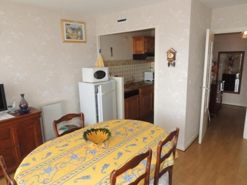 une cuisine avec une table et un réfrigérateur blanc dans l'établissement Appartement lumineux Centre Royan proche plage avec parking - FR-1-71-62, à Royan