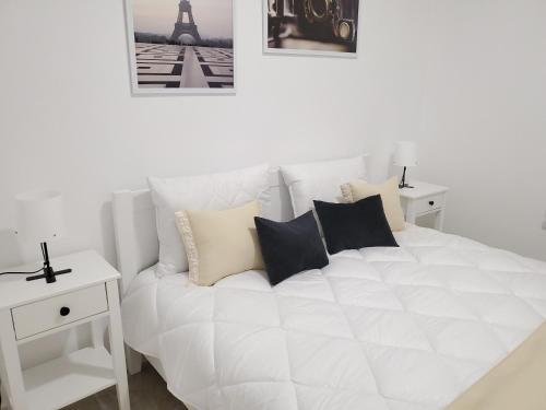 - une chambre avec un lit blanc doté d'oreillers et la tour Eiffel dans l'établissement VINNA Просторі апартаменти в новобудові., à Ternopil