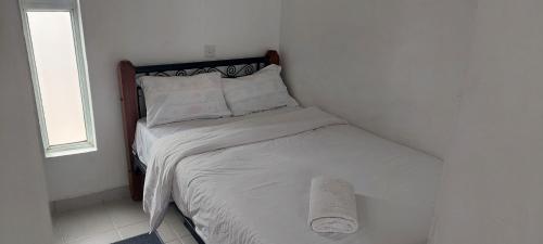 a bed in a white bedroom with a window at Ngong Road Studio in Nairobi