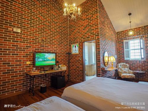 a brick walled bedroom with a bed and a television at 墾丁勿忘我城堡莊園 in Hengchun